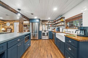 A modern kitchen with wooden flooring, stainless steel appliances, and blue cabinetry.