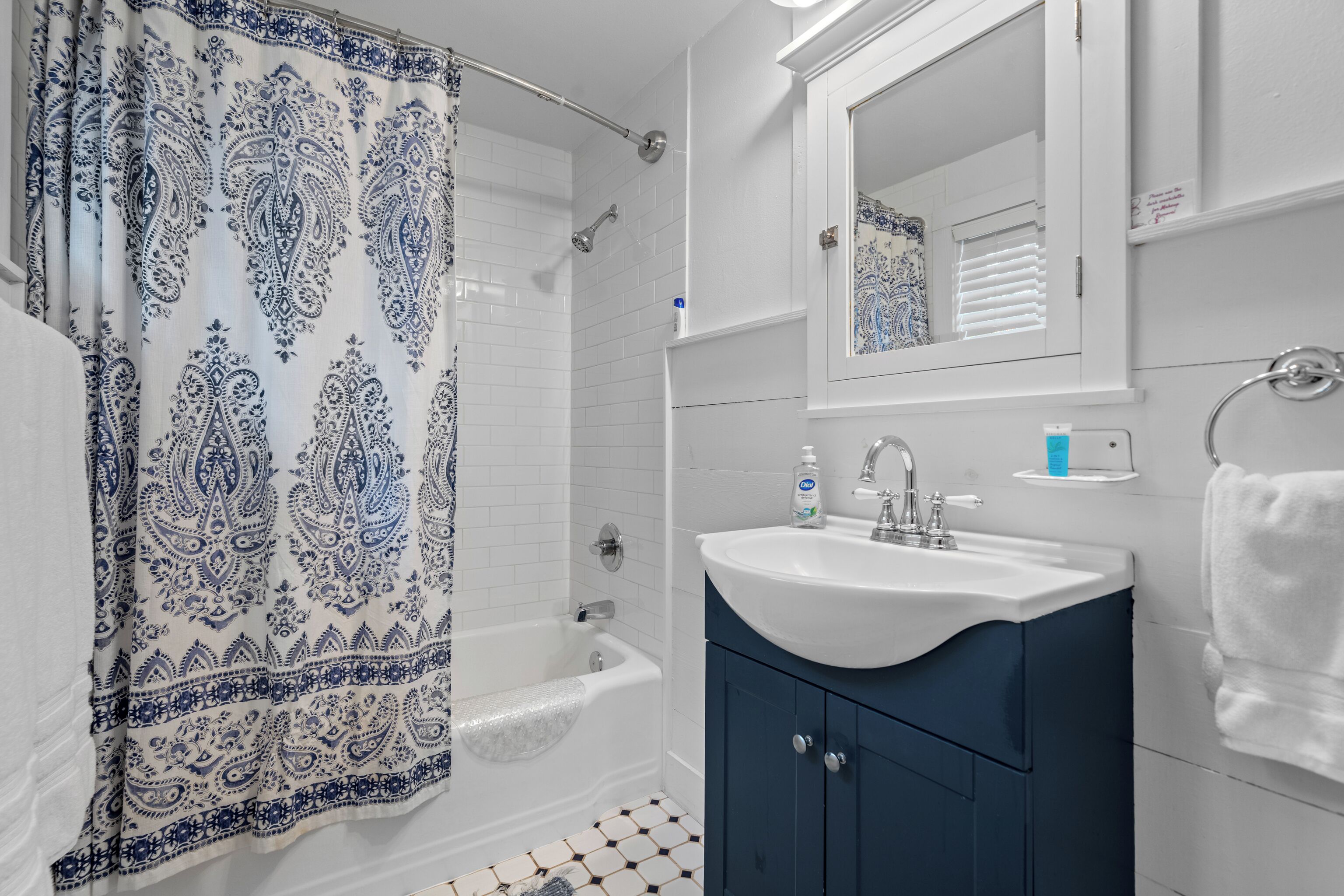Une salle de bain avec un rideau de douche, un lavabo, un miroir et un porte-serviettes.
