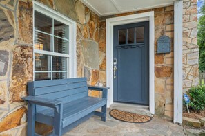 A stone exterior with a blue door and a bench in front.