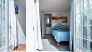 Een slaapkamer met een bed, een deur en een zichtbare badkamer door een open deur.