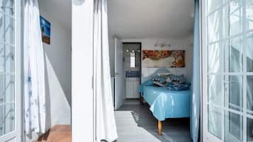 Une chambre à coucher avec un lit, une porte et une salle de bain visible à travers une porte ouverte.