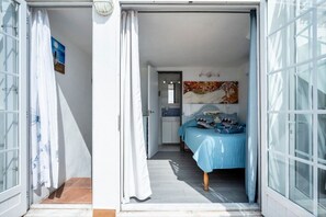 A bedroom with a bed, a door, and a bathroom visible through an open door. - Casa Teresa — city house with sea view (Olhão)