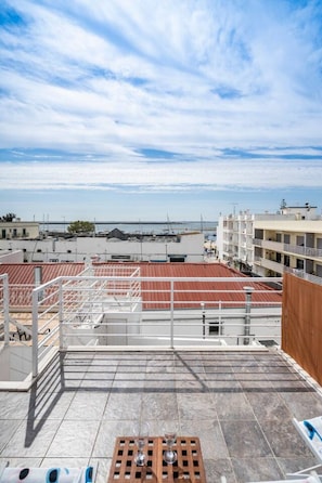 A rooftop terrace with a view of the sea, a red roof, and a building with multiple floors. - Casa Teresa — city house with sea view (Olhão)