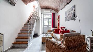 Una escalera que lleva a una puerta, una sala de estar con muebles de mimbre y un cuadro en la pared.