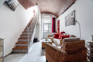 Una escalera que lleva a una puerta, una sala de estar con muebles de mimbre y un cuadro en la pared.