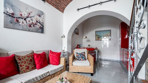 Een woonkamer met een bank, fauteuil, en een eethoek met een tafel en stoelen.
