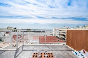 A rooftop terrace with a view of the sea, a wooden fence, and a table with a glass. - Casa Teresa — city house with sea view (Olhão)