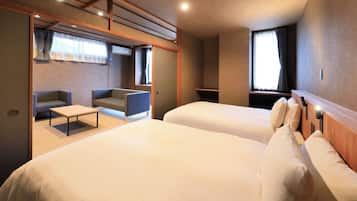 A hotel room with two beds, a sofa, a small table, and a window with curtains.