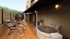 A wooden deck with lounge chairs and a hot tub.