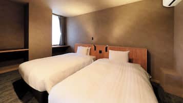 Ein Hotelzimmer mit zwei Betten, einem Fenster mit Vorhängen und einer Klimaanlage.