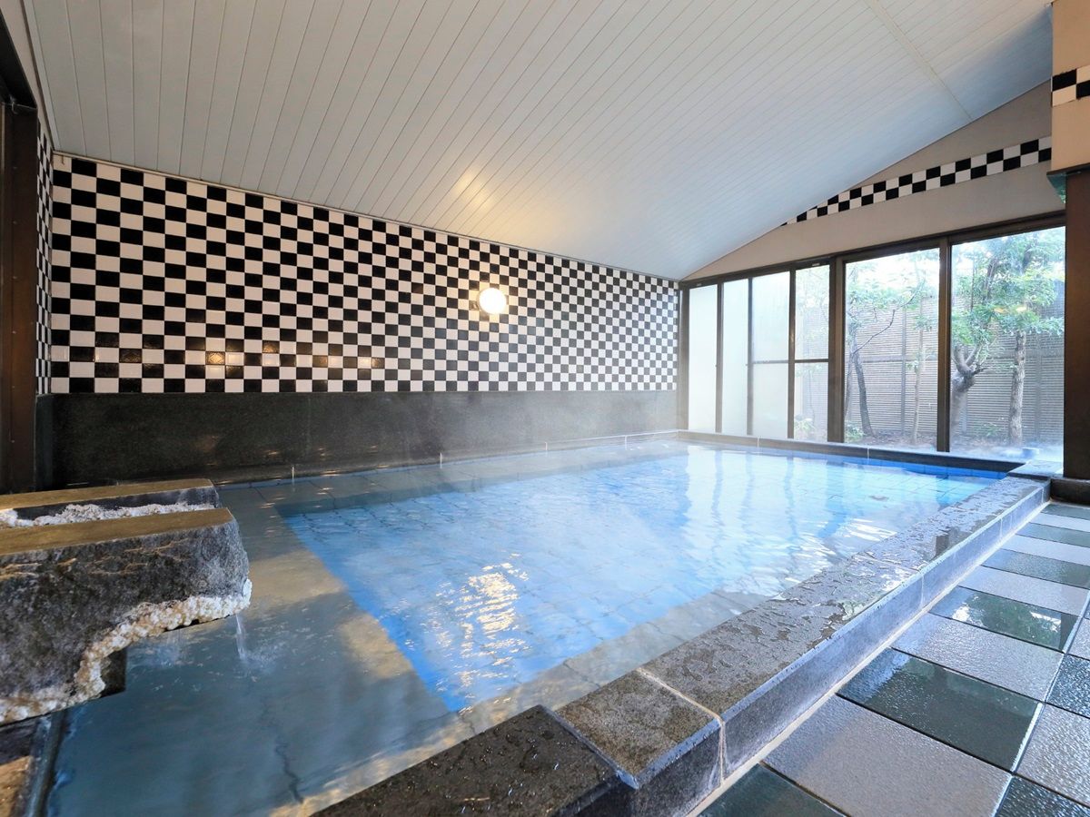 An indoor swimming pool with checkered walls and a stone edge.