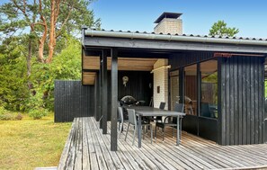 Eine Holzdiele mit Tisch, Stühlen, einem Grill und einem Ziegelkamin.