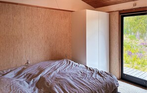 A bedroom with a bed, a large window, and a view of greenery. - Stunning home in Højby with WiFi (Højby)