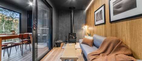 A cozy interior with a sofa, a table, chairs, a fireplace, and framed artwork on the wall.