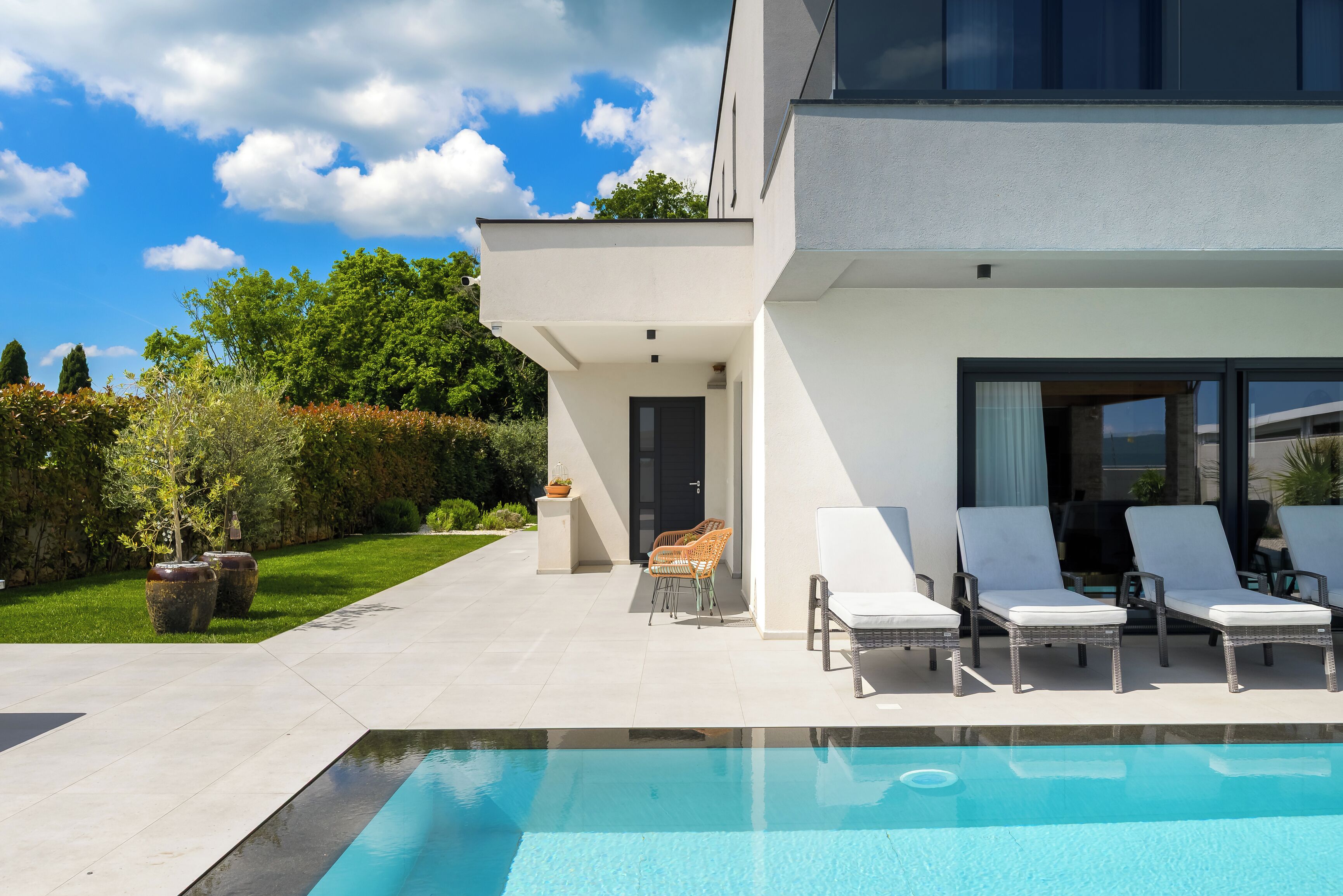 Une maison moderne dotée d’une piscine, d’un espace extérieur aménagé et d’un jardin bien entretenu.