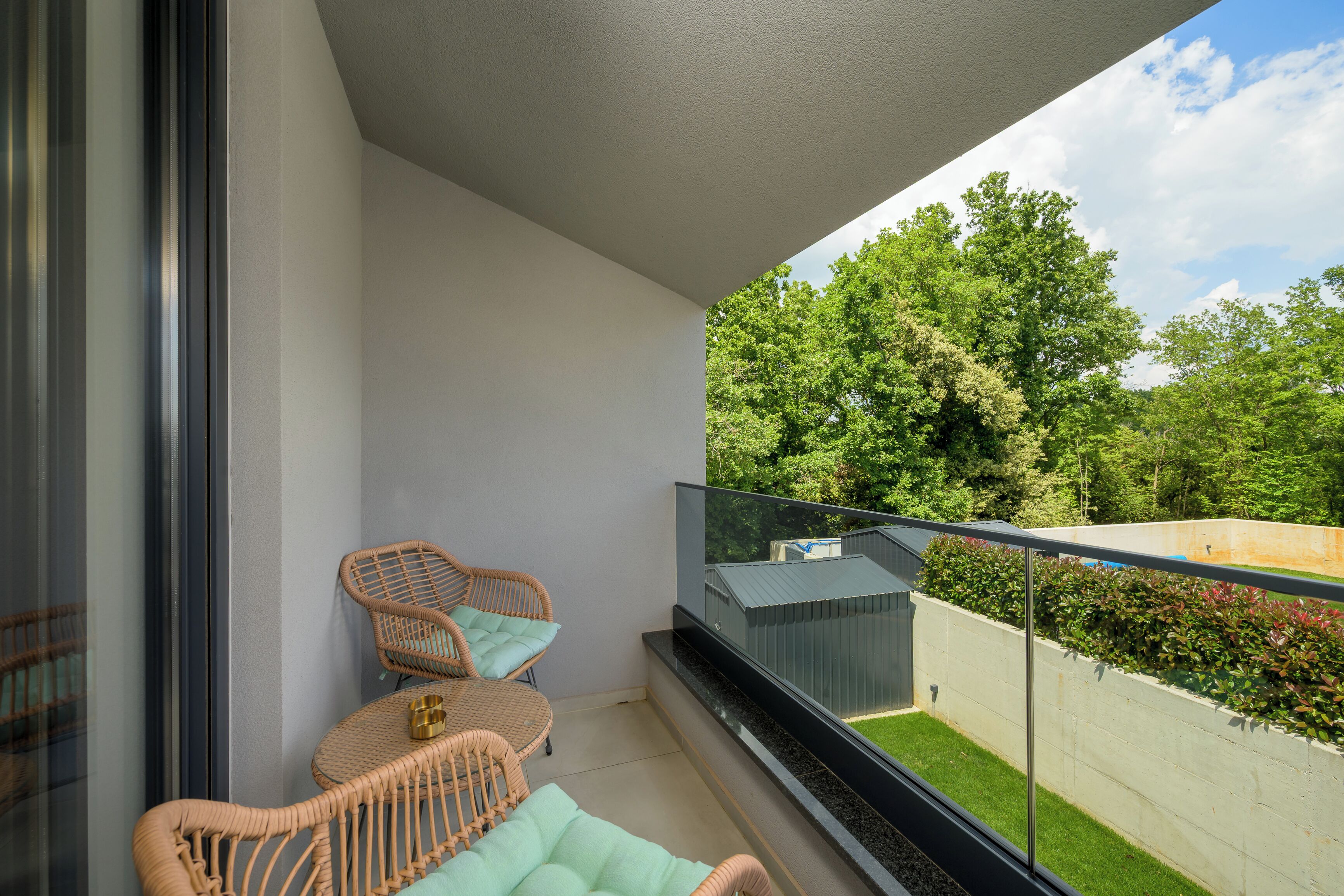 A balcony with wicker furniture and a view of greenery.