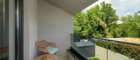 A balcony with wicker furniture and a view of greenery.