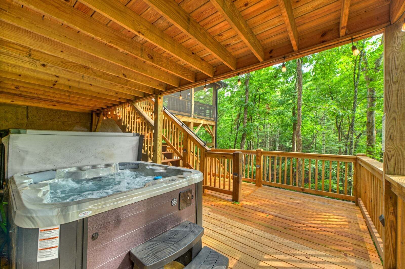 Un jacuzzi en una terraza de madera con vistas a un bosque.