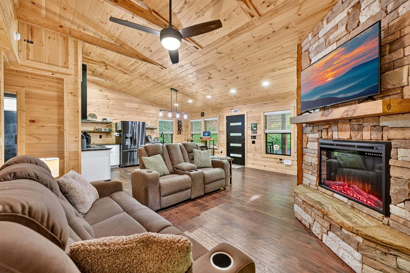 Un salon chaleureux avec une cheminée, des murs en bois et un ventilateur de plafond.