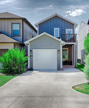 A residential house with a garage, a front porch, and a visible number '132' on the wall. - Cozy Newer Home Close to Lake Conroe, Pool, Golf Course, Tennis & Country Club! (Montgomery)