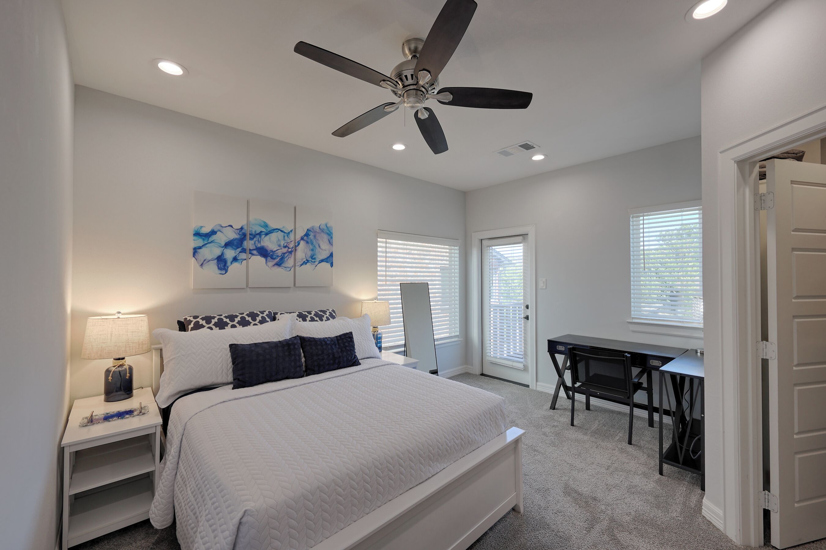 A bedroom with a bed, a desk, and a ceiling fan.
