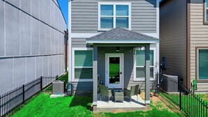 A two-story residential house with a covered porch, a front door, and a small patio area. - Cozy 2/2.5 Close to Lake Conroe, Pool, Golf Course, Tennis & Country Club! (Montgomery)