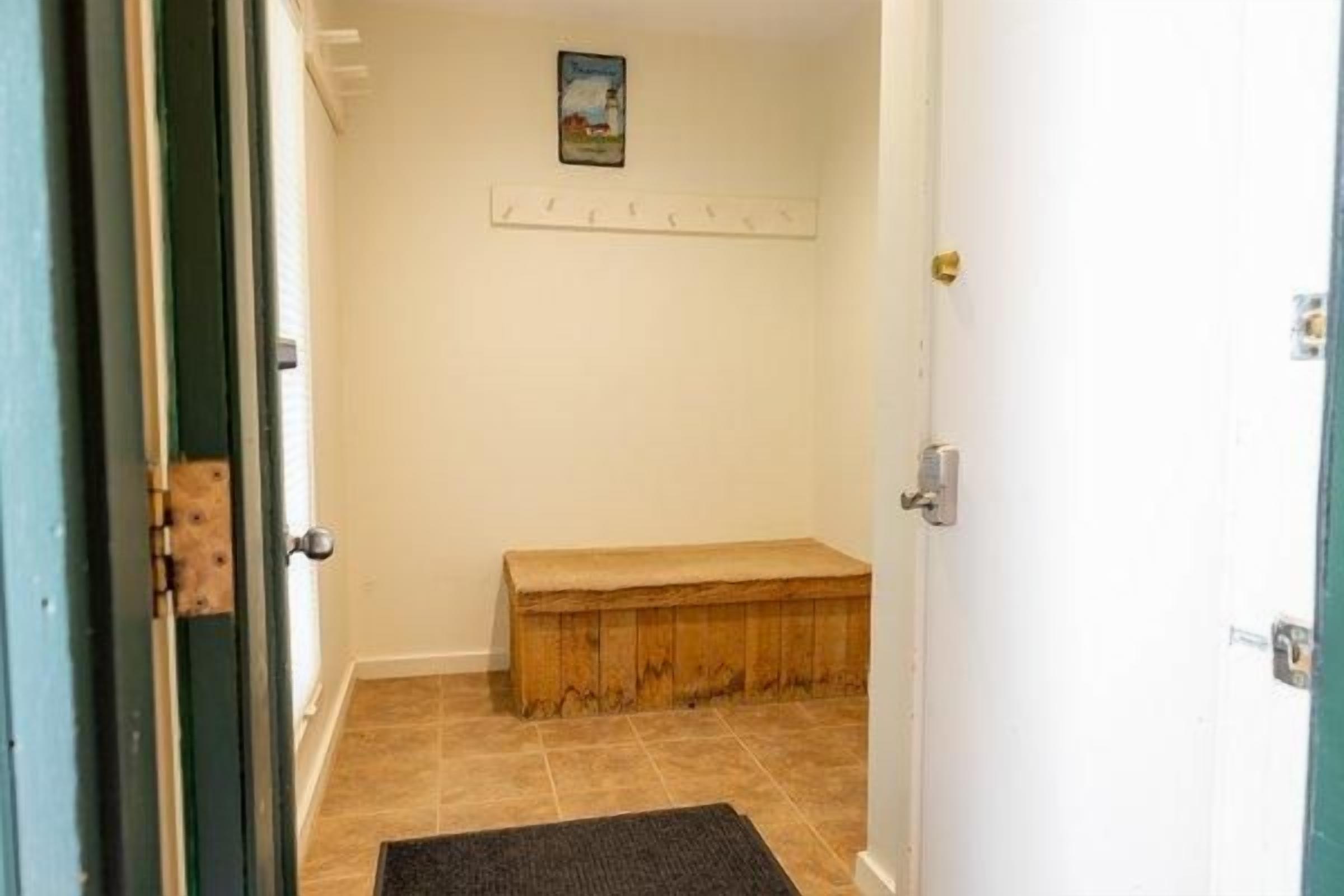 A hallway with a bench, a door, and a wall-mounted picture.