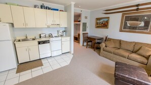 A compact living space with a kitchenette, a sofa, a dining table, and a framed picture on the wall.