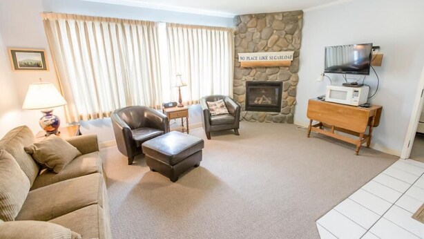 A living room with a stone fireplace, a television, and a sofa.