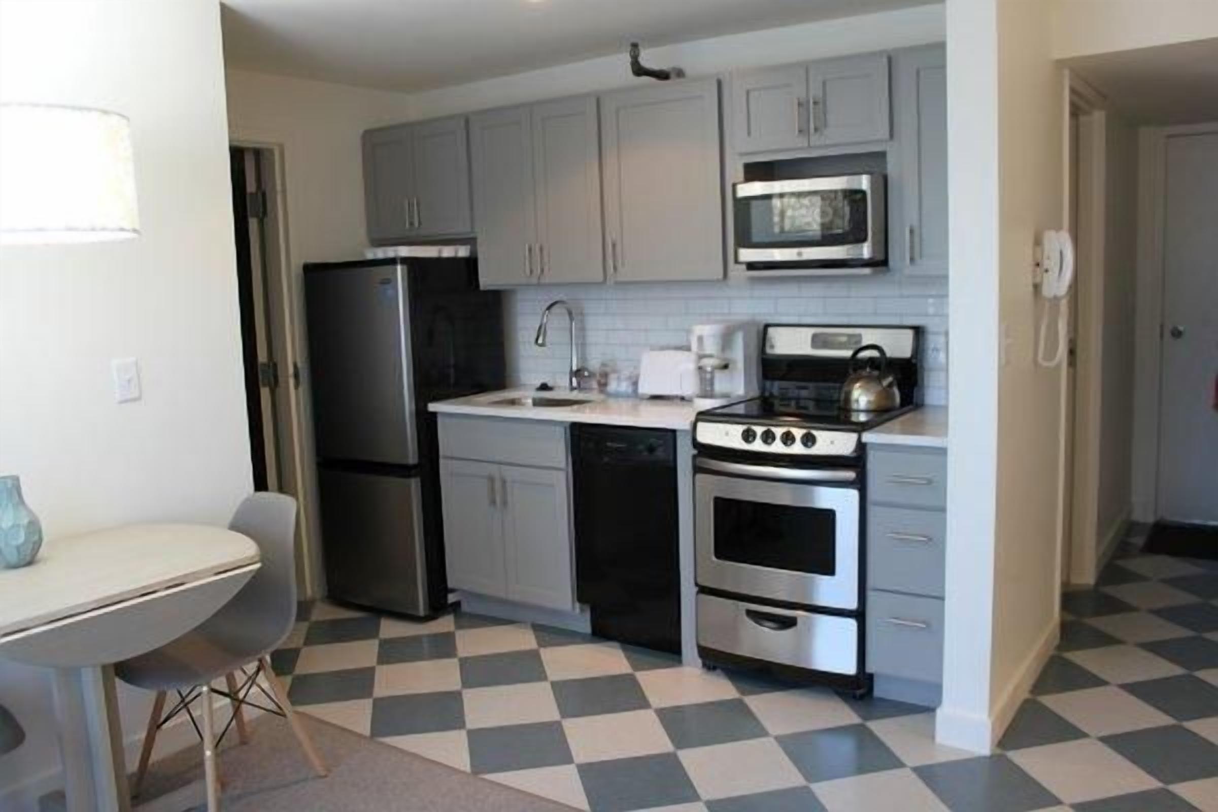 A compact kitchen with a refrigerator, microwave, stove, and sink.