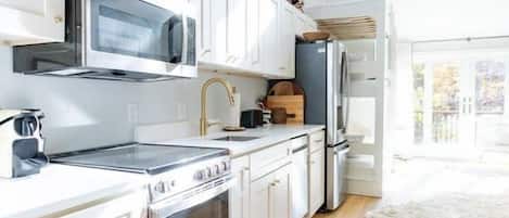 A modern kitchen with white cabinets, a microwave, stove, and refrigerator.