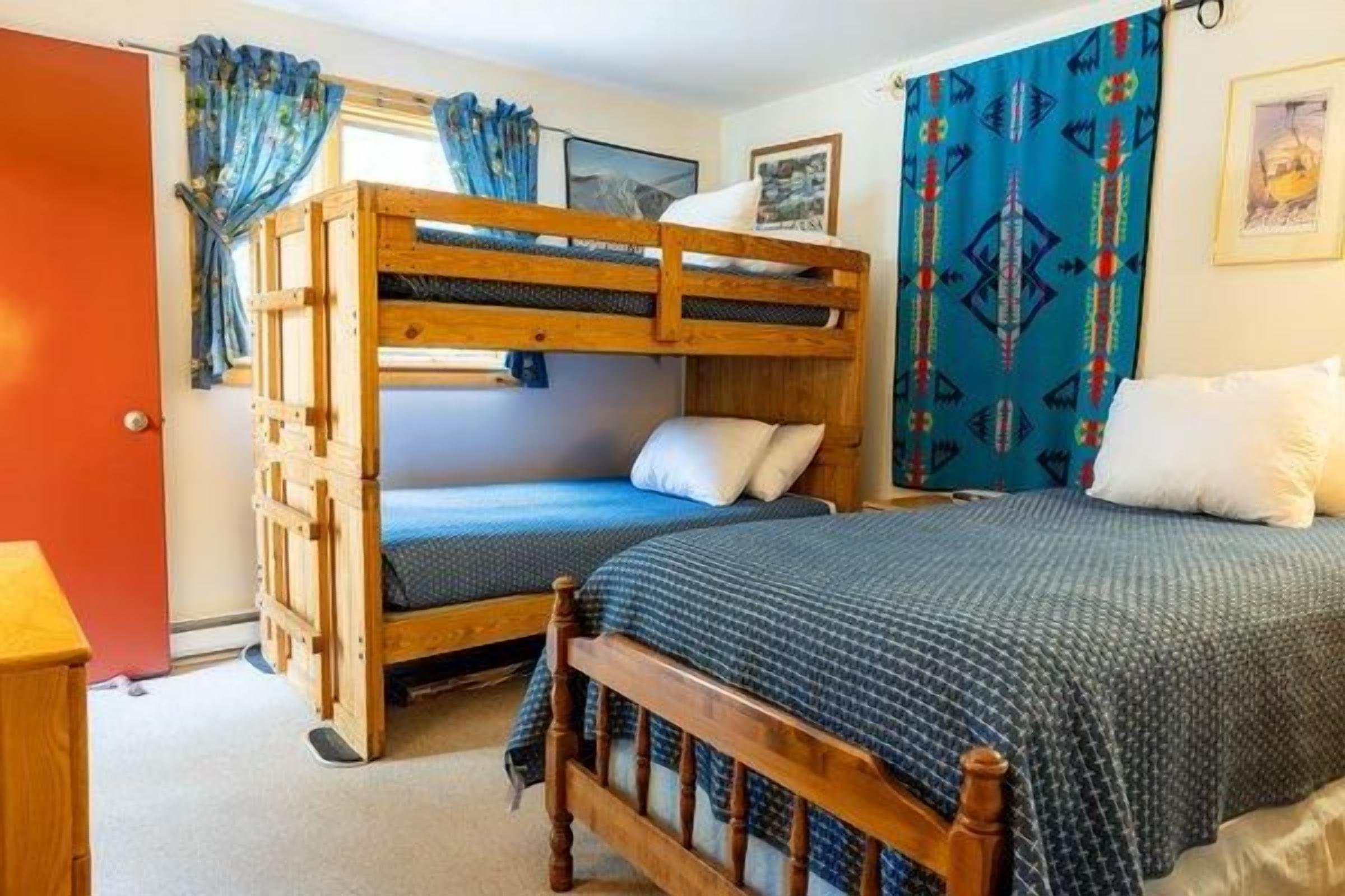 Una habitación con literas, un escritorio de madera y una ventana con cortinas.