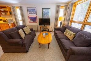 A living room with two sofas, a coffee table, a TV, and a fireplace. - Sugarloaf Mountain Snowbrook Village C2524 (Carrabassett Vly)