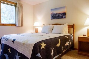 A bedroom with a bed, two bedside tables, a nightstand, a window with curtains, and a painting on the wall. - Sugarloaf Mountain Snowbrook Village C2524 (Carrabassett Vly)