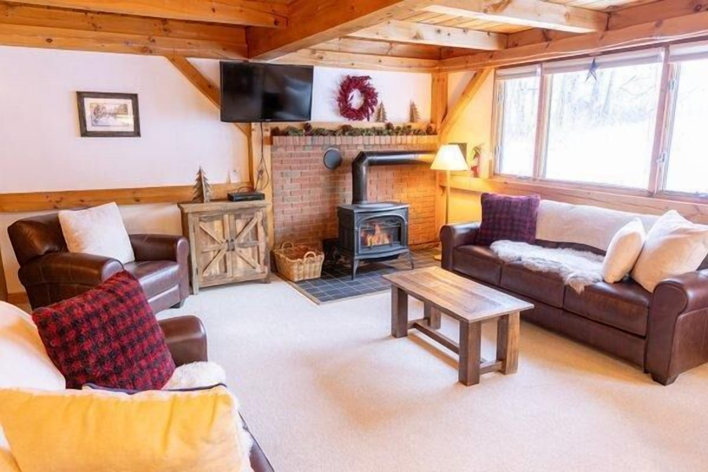 Una sala de estar acogedora con chimenea, sofás de cuero y televisión.