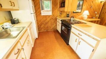 A compact kitchen with white cabinetry, a stove, and a sink.