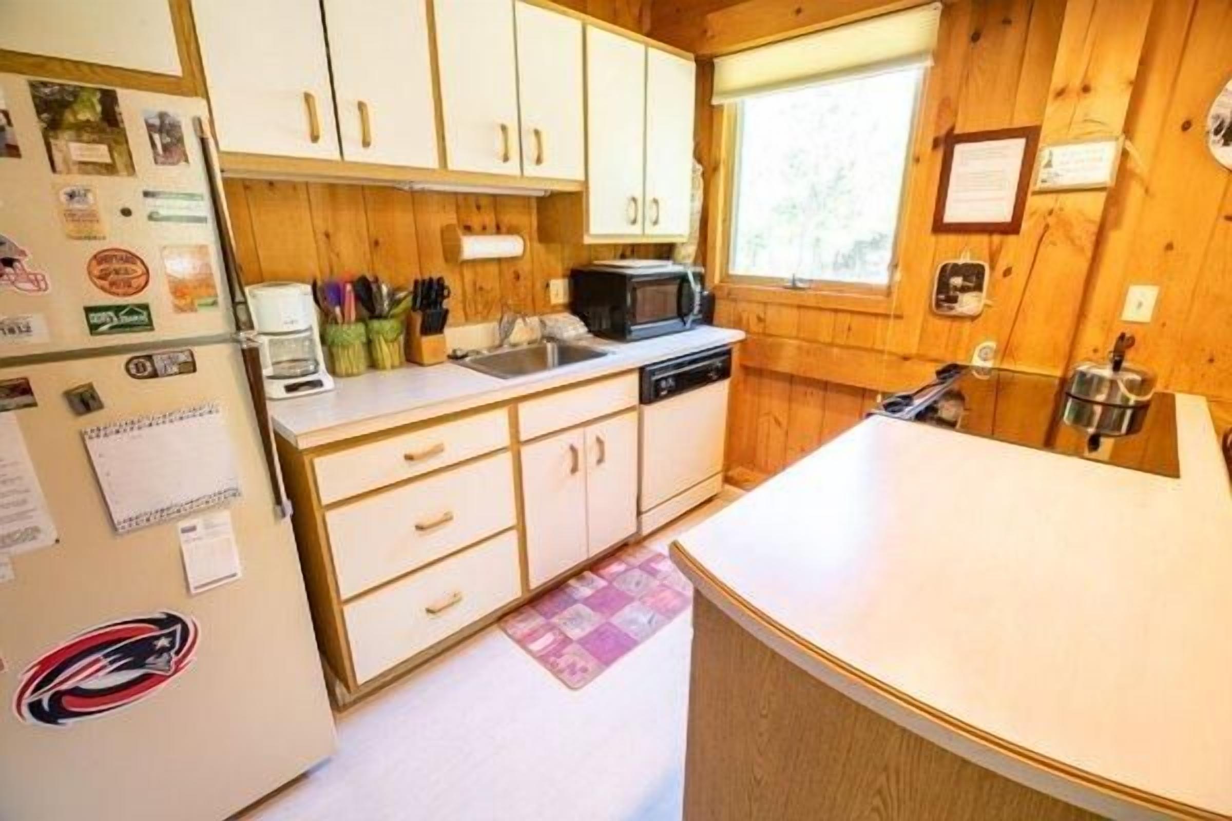A compact kitchen with wooden cabinets, a microwave, and a sink.