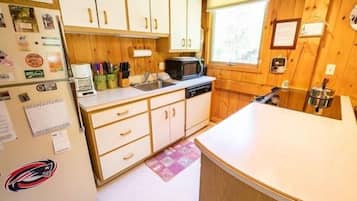 A compact kitchen with wooden cabinets, a microwave, and a sink.