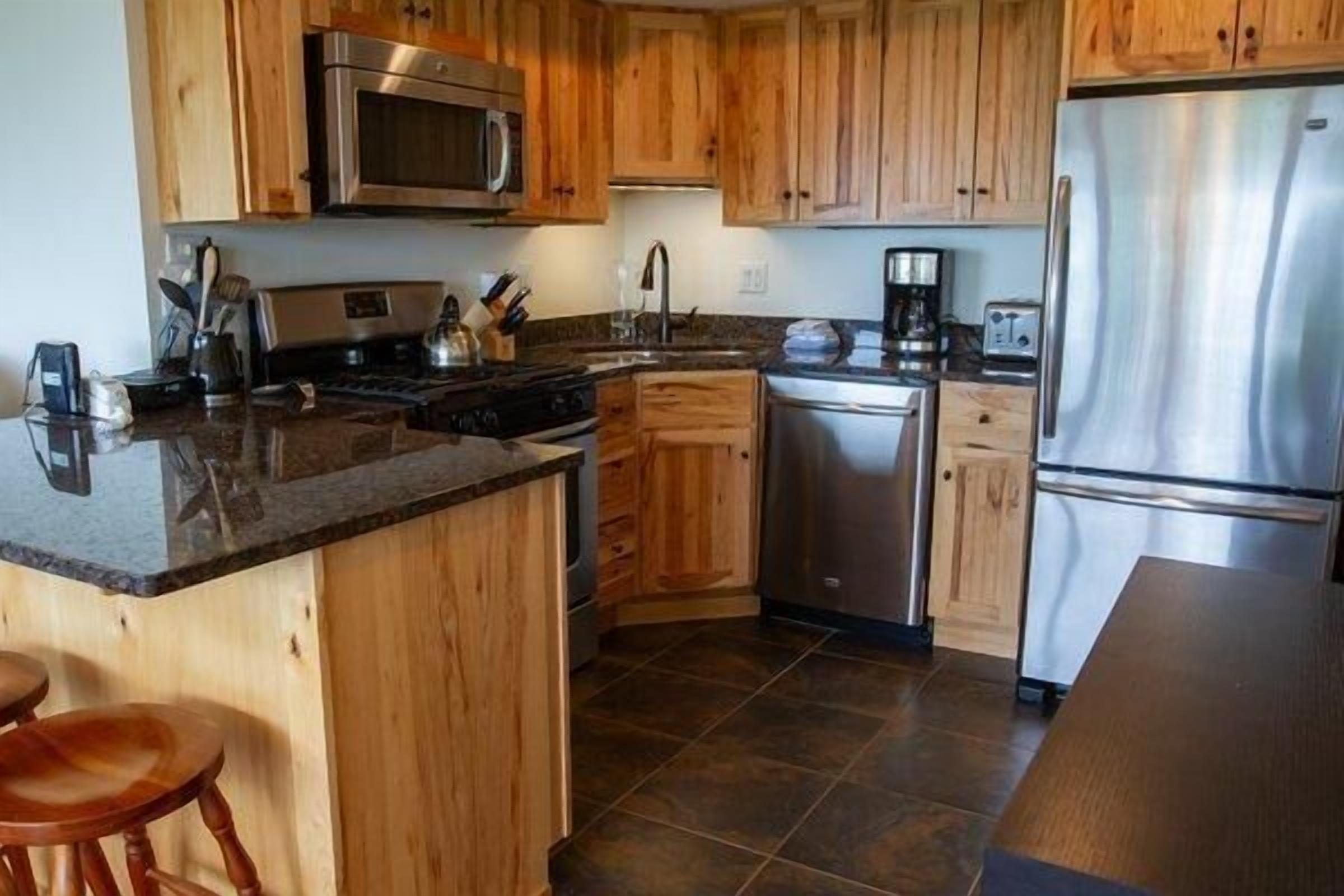 A kitchen with wooden cabinets, stainless steel appliances, a granite countertop, and a dishwasher.