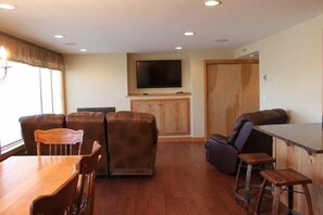 Una sala de estar con una mesa de comedor de madera, dos sofás, un televisor y un mueble de madera.