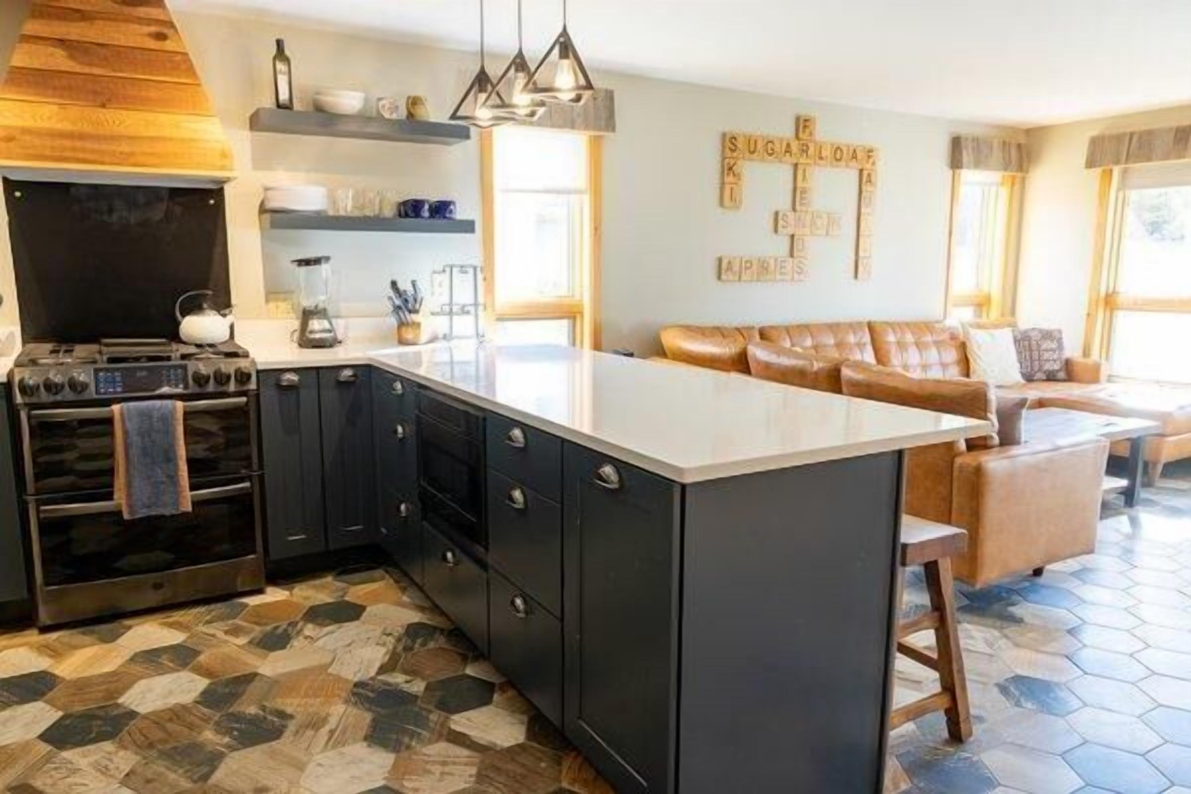 Une cuisine moderne dotée d’un îlot central, de meubles de couleur sombre et d’une grande cuisinière.