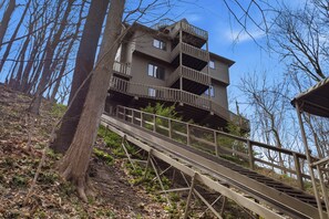 A multi-level wooden building with balconies, surrounded by trees and a wooden walkway leading to it. - Wavecrest Cottage-Sleeps 14 Beach (Laketown Township)
