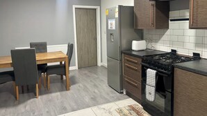Una cocina moderna con una mesa de comedor, sillas, un refrigerador, una estufa y armarios.