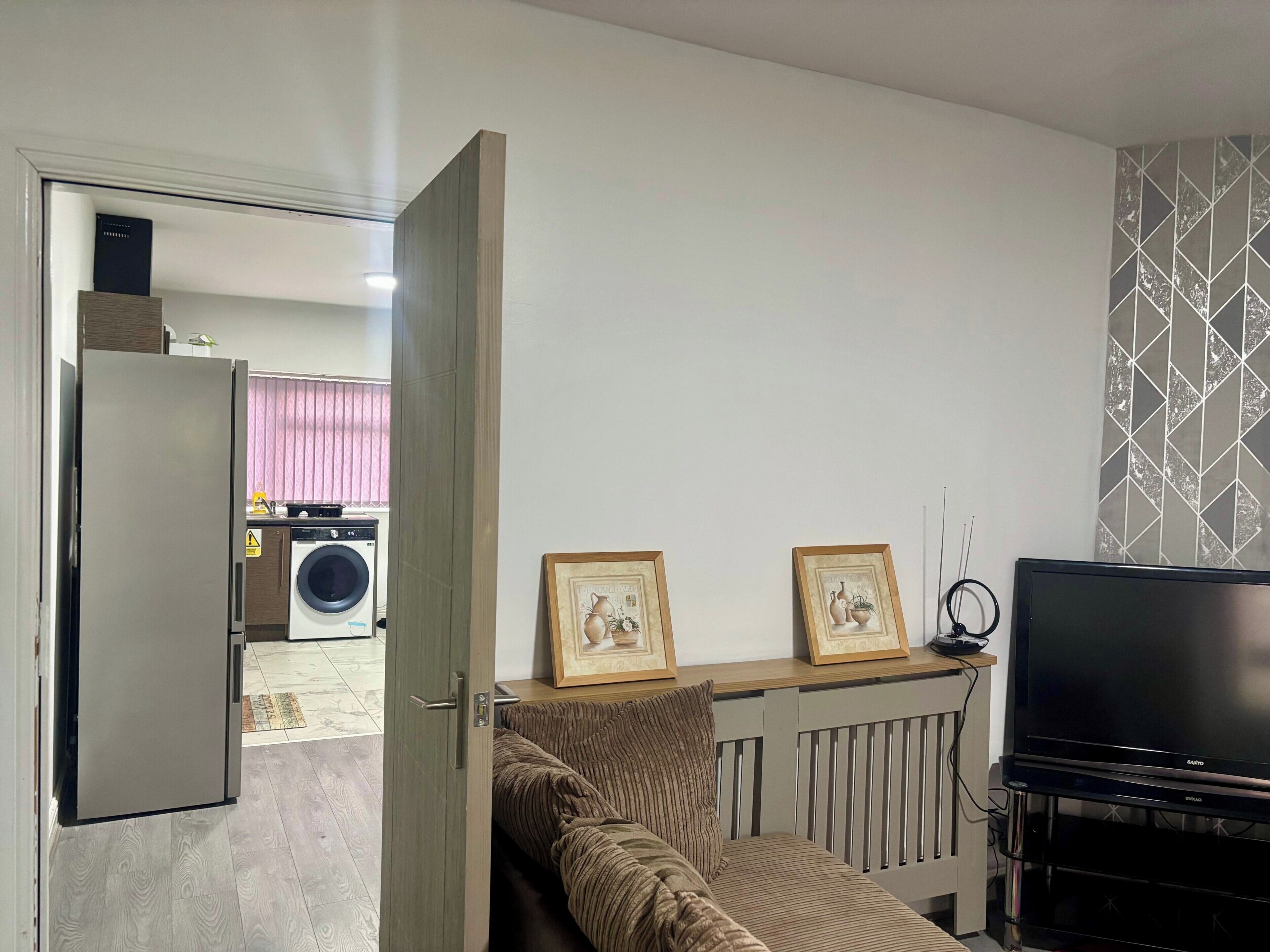 A living room with a sofa, a television, and framed pictures on the wall.