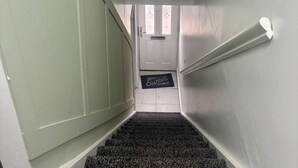 Una escalera que lleva a una puerta con un felpudo que dice 'Homes Sweet Home'.