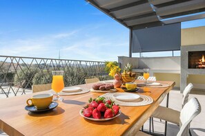A dining table set outdoors with a view of the landscape, a fire feature, and a variety of food items. - Vila Helios in Pomer by Istrabook (Pomer)