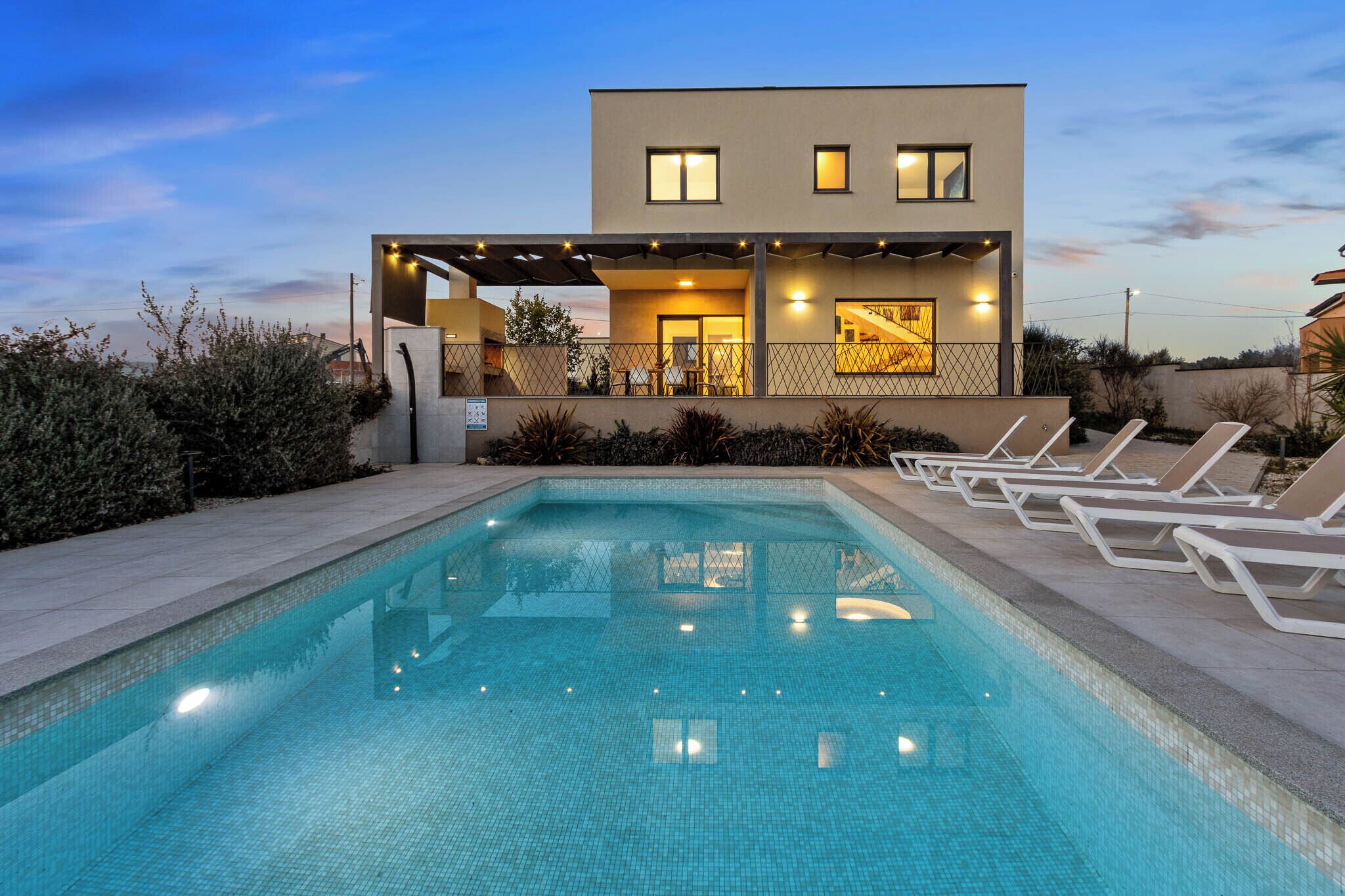 A modern building with a swimming pool and lounge chairs.