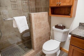 Een badkamer met een douche, toilet en een handdoekrek.