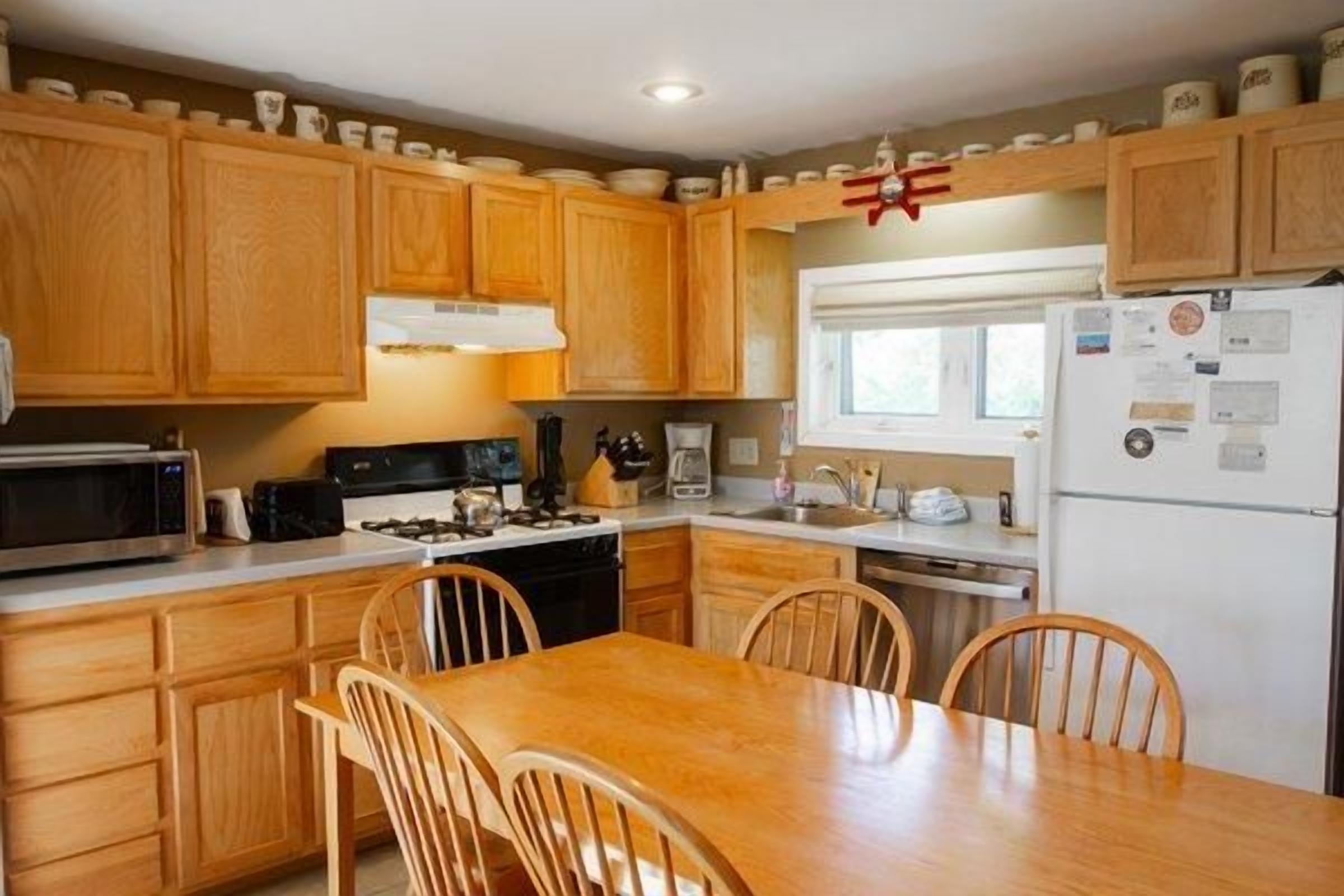 A kitchen with wooden cabinets, a stove, microwave, and a dining table with chairs.