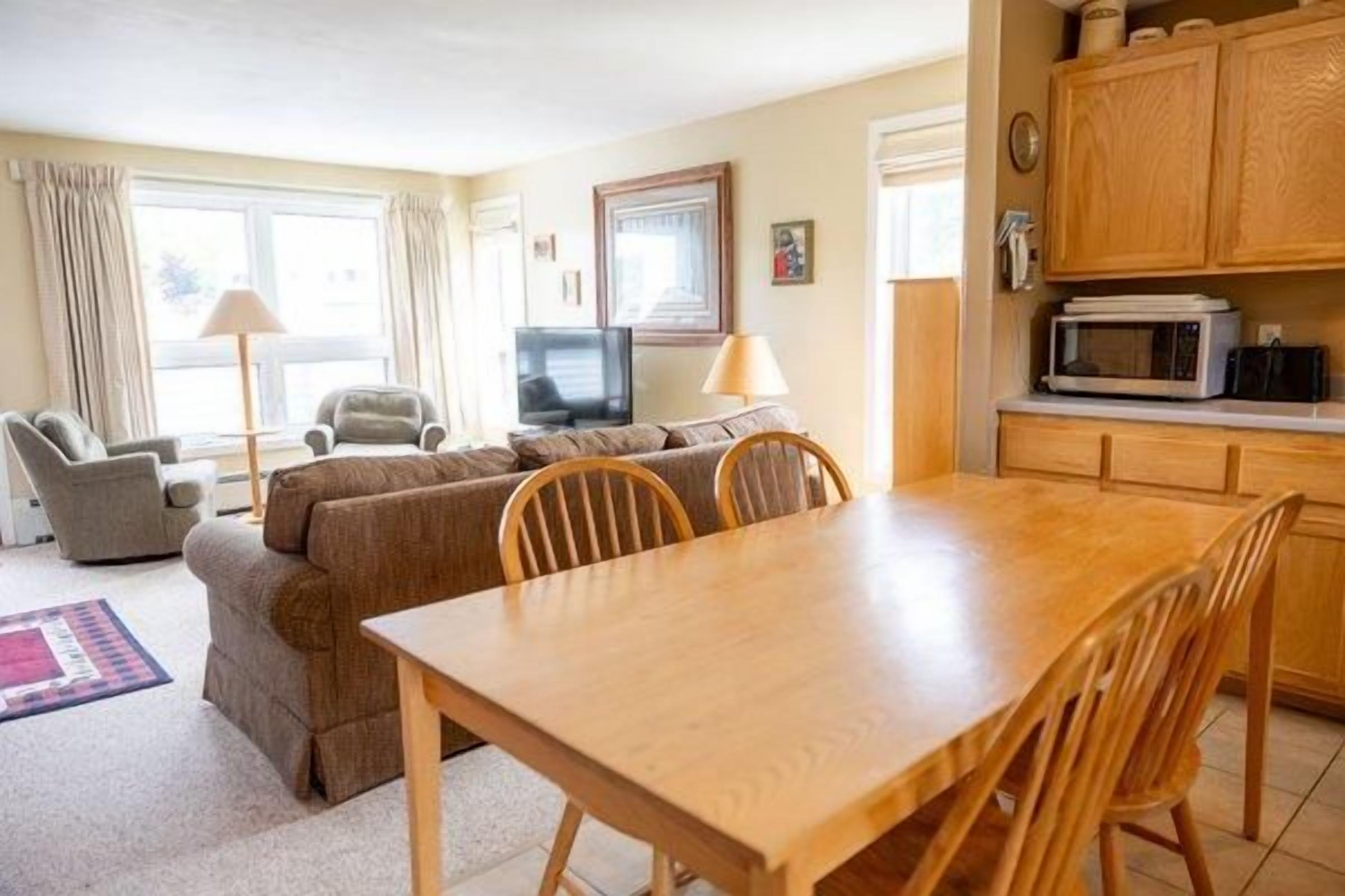 A living room with a sofa, chairs, a TV, and a dining table.